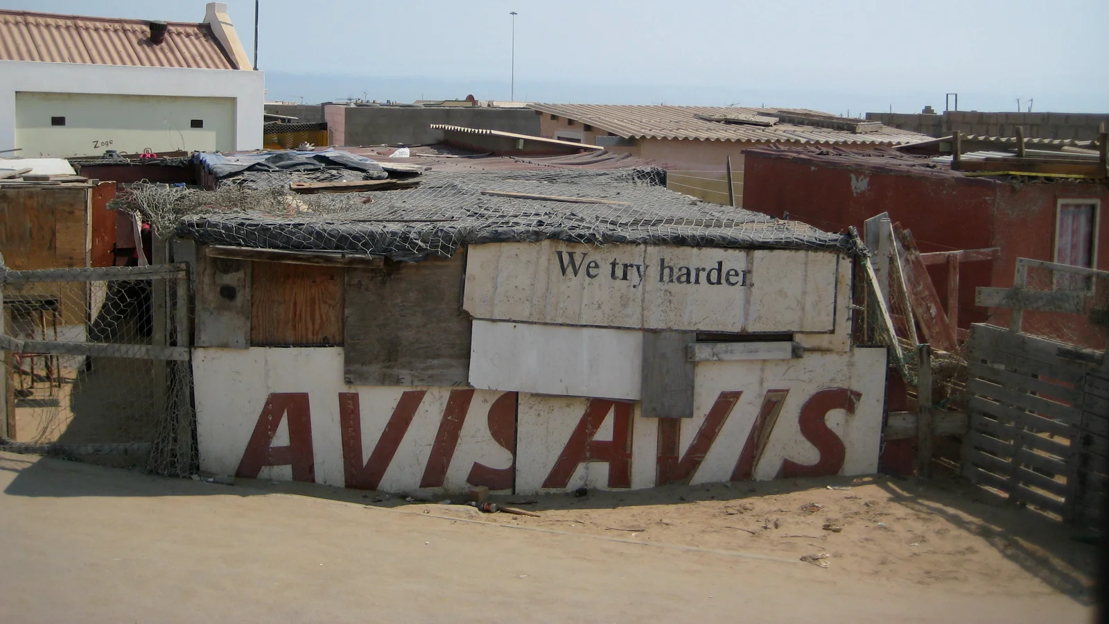 Vecchia insegna Avis con lo slogan We try harder riutilizzata come parete di una casa in Namibia, esempio di posizionamento di marca durato decenni